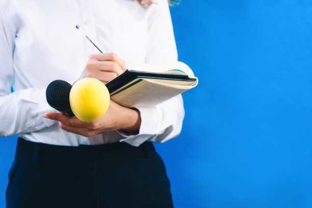 一个陌生的女记者拿着笔记本，一支笔和两个麦克风问问题。新闻和报道的概念。图片下载