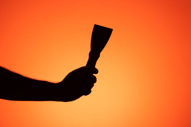 手的剪影与明亮的色彩背景的抹刀。图片下载