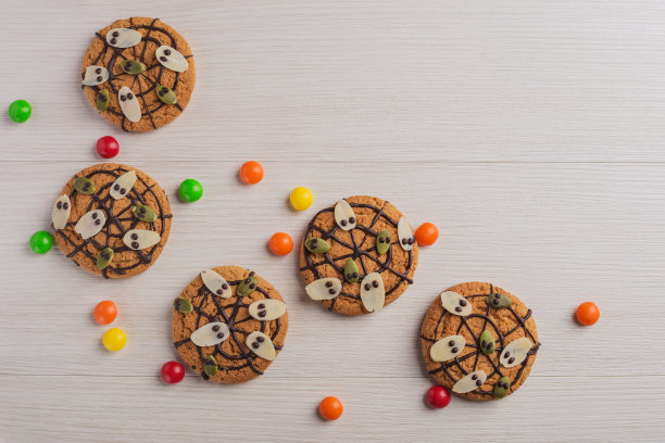万圣节饼干上有鬼魂，白色木桌上有蜘蛛网。秋天，万圣节的概念。图片下载