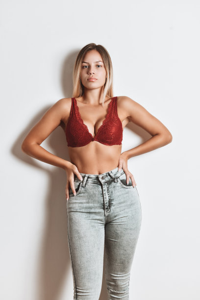 金发美女在胸罩和牛仔裤摆姿势在白色背景图片下载