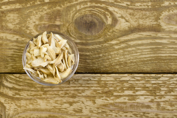 干蒜片在黑色盘子上近距离平放照片在灰色纹理的木制背景图片下载