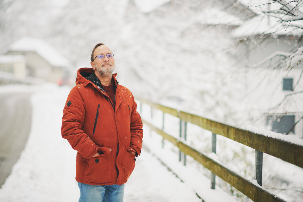 户外肖像中年男子，55 - 60岁，享受美好的寒冷天气，穿着红橙色的冬季夹克图片下载