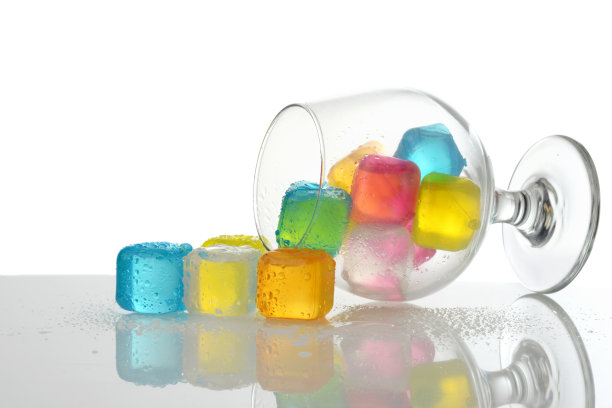 在白兰地酒杯中洒出彩色塑料冰块图片下载
