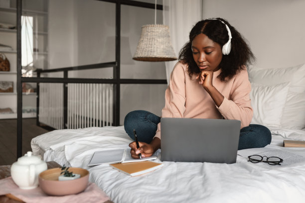 黑人女学生在家用笔记本电脑学习记笔记图片下载
