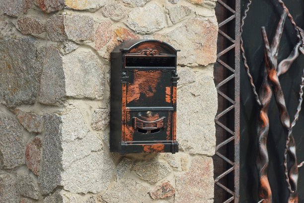灰色的石墙上挂着一个彩色的金属邮筒图片下载