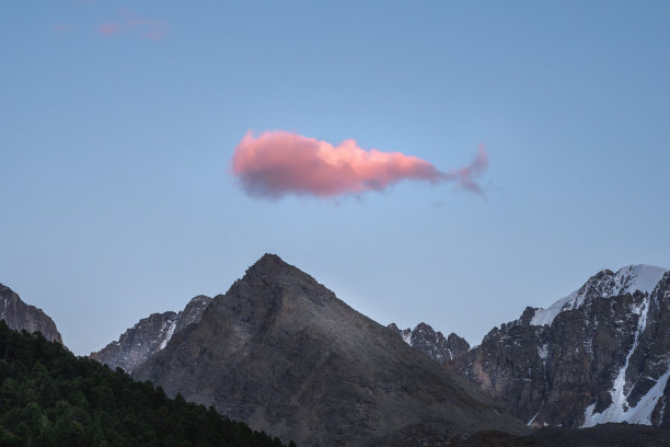 像鲸鱼一样的粉红色大云漂浮在群山的夜空上。图片下载