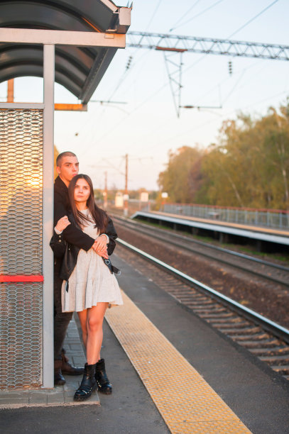一个年轻的男孩和一个女孩站在站台上拥抱在一起。傍晚,夕阳图片下载