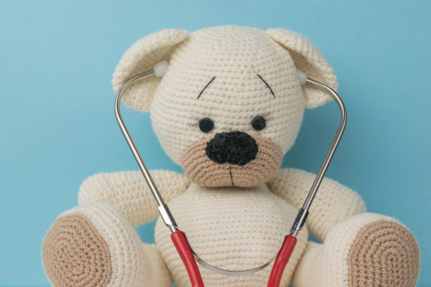 蓝色背景上有红色听诊器的针织熊。图片下载
