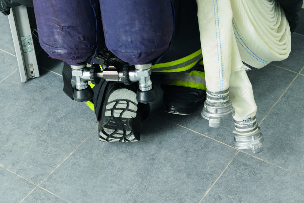 一个消防队员带着设备爬过一扇开着的门去扑灭一场火灾，这是一个特写镜头图片下载