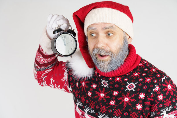 圣诞老人把闹钟放在耳边。图片下载