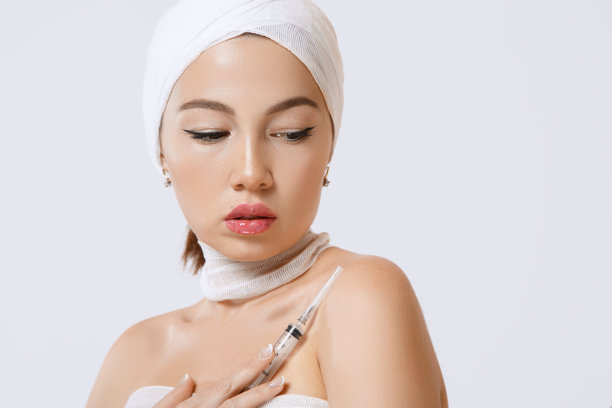 一个年轻美丽的亚洲女人的时尚肖像在一个孤立的背景下，手里拿着一个注射器。注射器里装有美容用药物的注射剂图片下载