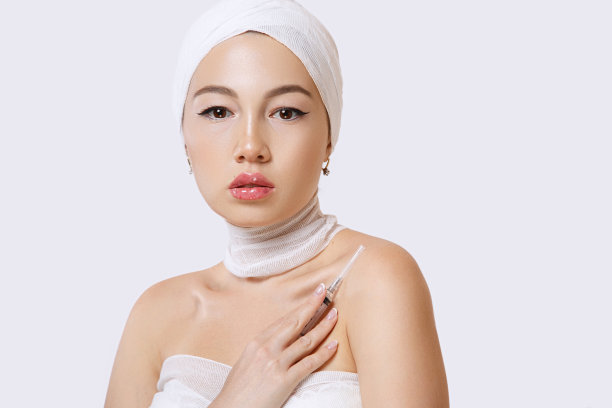 一个年轻美丽的亚洲女人的时尚肖像在一个孤立的背景下，手里拿着一个注射器。注射器里装有美容用药物的注射剂图片下载