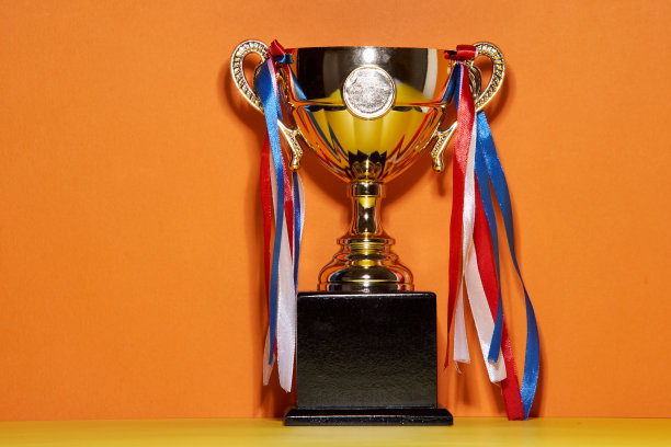 橙色背景下金色奖杯的特写图片下载