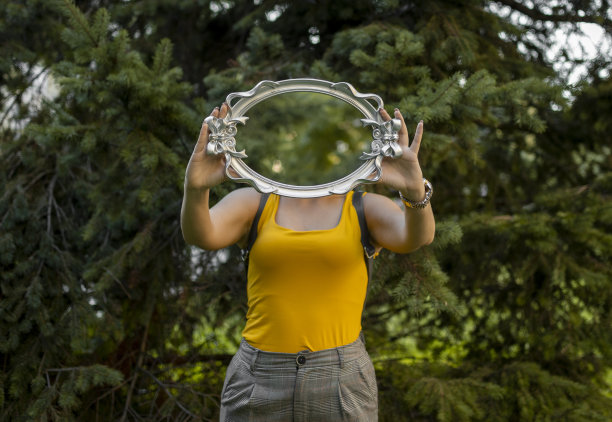 一个穿黄衬衫的女人，手里拿着一面镜子。图片下载