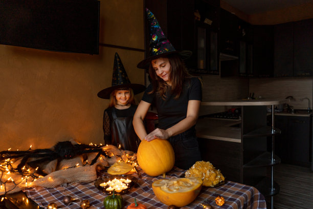 妈妈女儿在雕刻南瓜。为万圣节做准备。图片下载