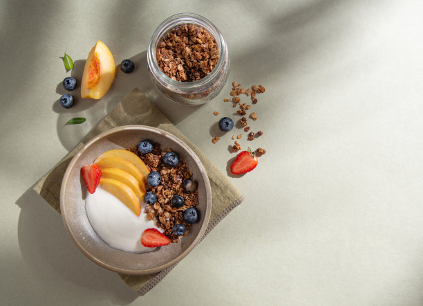 美味的天然酸奶与自制格兰诺拉麦片，桃子，浆果在碗和罐子与麦片在绿色背景的清晨阴影。健康营养的早餐。减肥食品。俯视图和复制空间图片下载