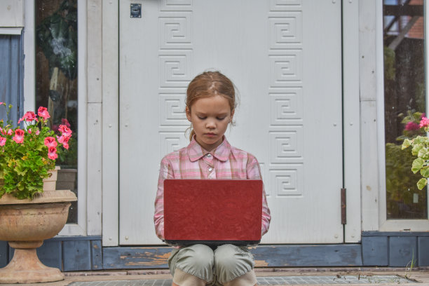 一个女孩带着笔记本电脑坐在房子的门廊上上课，在没有滤镜的远程照片上图片下载