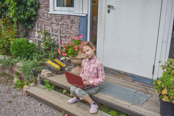一个女孩带着笔记本电脑坐在房子的门廊上上课，在没有滤镜的远程照片上图片下载