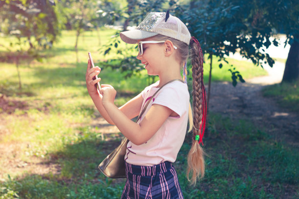 可爱的小女孩与长辫子在棒球帽户外阳光的日子青年文化生活方式真实的照片图片下载