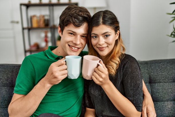 年轻的白人夫妇在家微笑喝咖啡图片下载