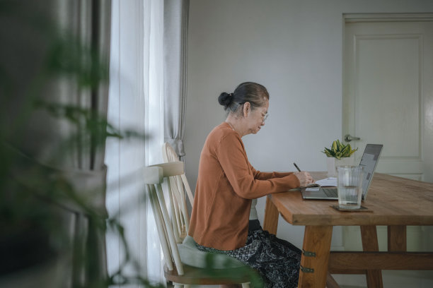 亚洲妇女在餐桌上写便条/信。图片下载