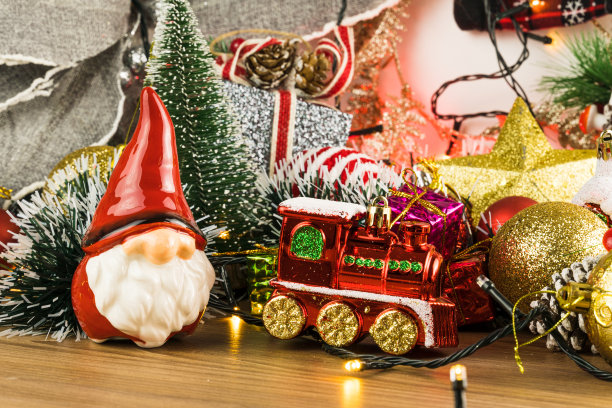 有圣诞装饰的木桌。红色、银色和金色的球、礼品盒、彩灯、圣诞老人、潘妮朵妮、圣诞树等。有选择性的重点图片下载