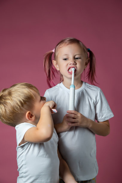 微笑的白种人小男孩和小女孩正在刷牙图片下载