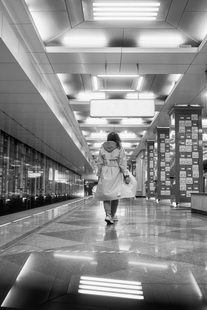 穿着米色风衣的女孩在地铁站台上等车图片下载