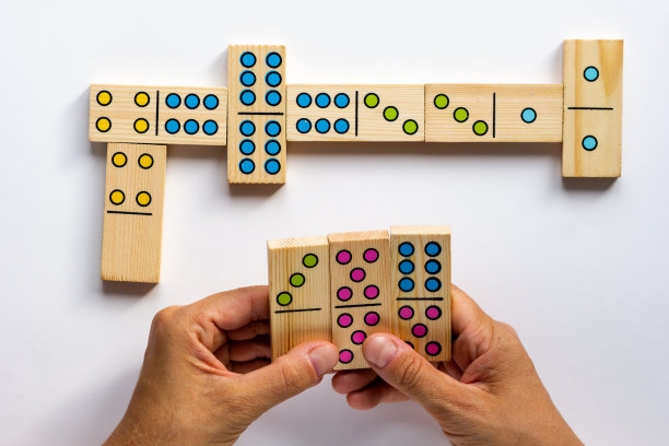 俯视图的女人手握木制多米诺骨牌游戏块在白色的背景图片下载