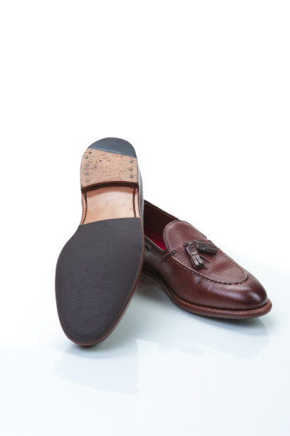 鞋的概念。一双传统正式时尚的棕色卵石粒流苏乐福鞋在白色反射表面上相互。垂直的图像图片下载