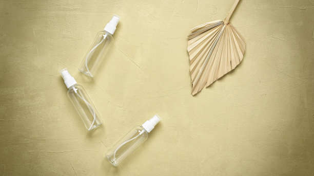 化妆品喷雾透明瓶干棕榈叶上米色灰泥背景。俯视图，平铺，复制空间。横幅、健美的形象。图片下载