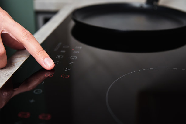 女人在厨房里用手打开现代化的电磁炉图片下载