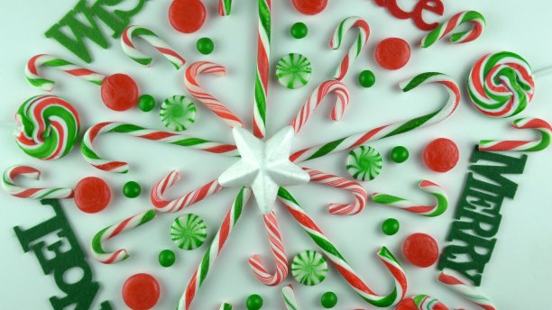 传统的冬季节日圣诞节糖果手杖装饰品，肉桂、薄荷糖棒甜点排列在白色桌子上。装饰成带有文字“欢乐”、“圣诞”、“和平”、“快乐”、“愿望”的雪花图片下载