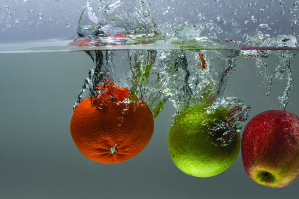 背景是桔子和苹果落入水中的特写镜头。华丽的背景。图片下载