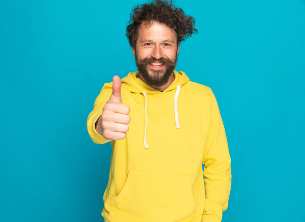 穿黄色连帽衫的快乐年轻人竖起大拇指图片下载