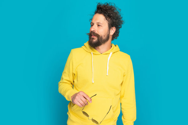 穿着黄色连帽衫的帅气年轻男子向旁边张望图片下载