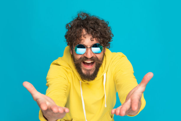 穿着黄色连帽衫的快乐年轻人张开双臂，展示图片下载