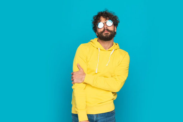 自信性感的男人穿着黄色连帽衫戴着墨镜摆姿势图片下载