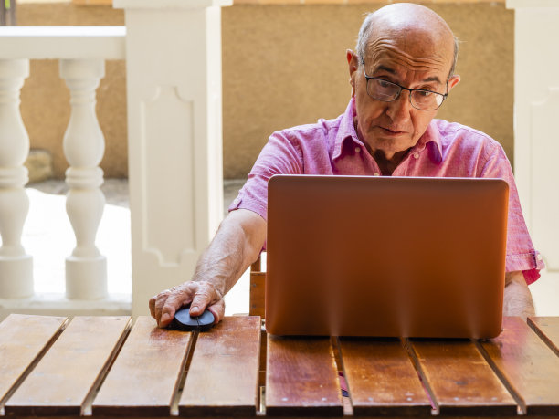 一位正在用笔记本电脑工作的老人感到惊讶。图片下载