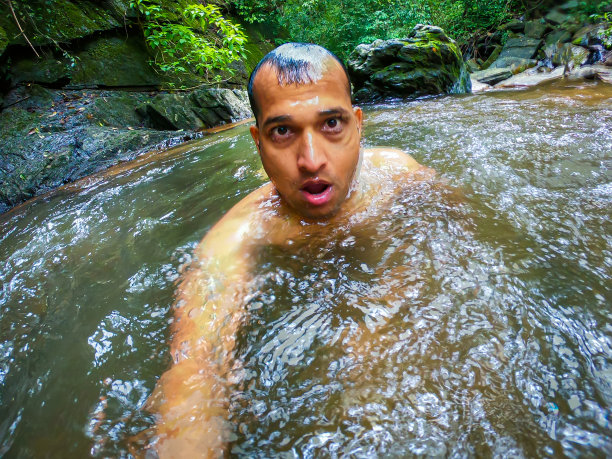 清晨，男人在森林的天然瀑布中沐浴，从不同的角度图片下载