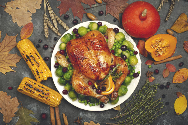 感恩节晚餐用的火鸡或鸡肉。感恩节的食物背景与秋天的季节性特色菜。炸鸡南瓜，蔬菜和秋天的装饰木制的桌子背景。图片下载