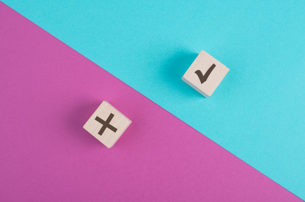 木制立方体，在粉红色和蓝色的充满活力的背景上打勾和交叉，极简主义图片下载