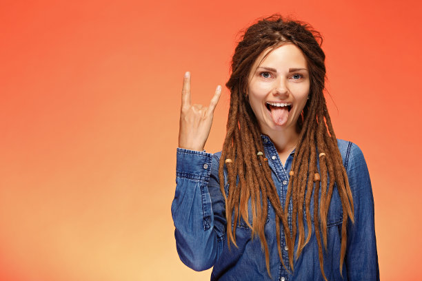 有趣的年轻女子向摄像机展示她的舌头和角的手势图片下载