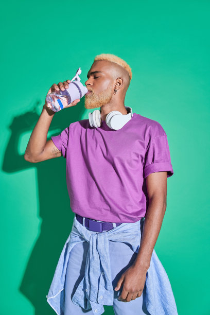 一名男子手持透明瓶子，一边拍照一边贪婪地喝酒图片下载