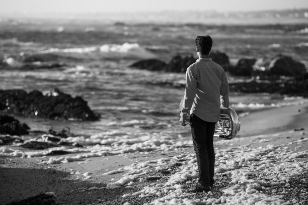 海边一个吹着大号的音乐家。黑白照片。图片下载