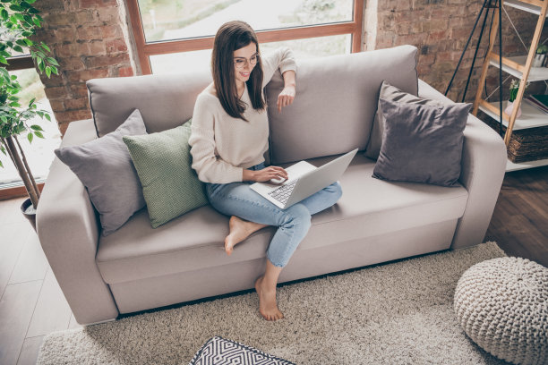 上面的高角度看美女工作照片，坐在沙发上，在家里客厅里用电脑浏览，戴上眼镜图片下载