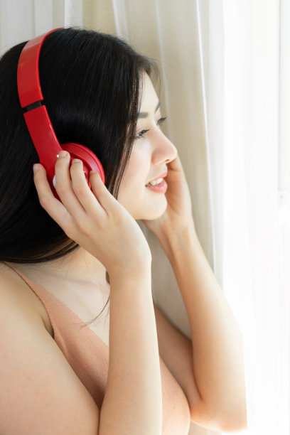 生活方式美丽的亚洲女人可爱的女孩感到幸福享受耳机听音乐耳机在白色的卧室图片下载