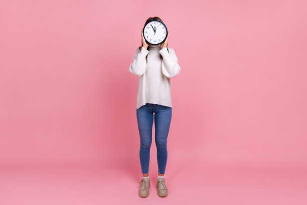 全身画像的不知名的女人隐藏她的脸背后的大挂钟，显示时间走。图片下载