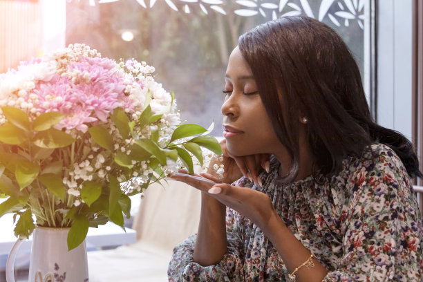 闭着眼睛嗅着花束的非洲女孩图片下载