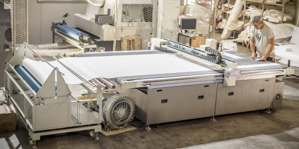 技术人员在数控数字切割机上工作，用于切割纺织品图片下载